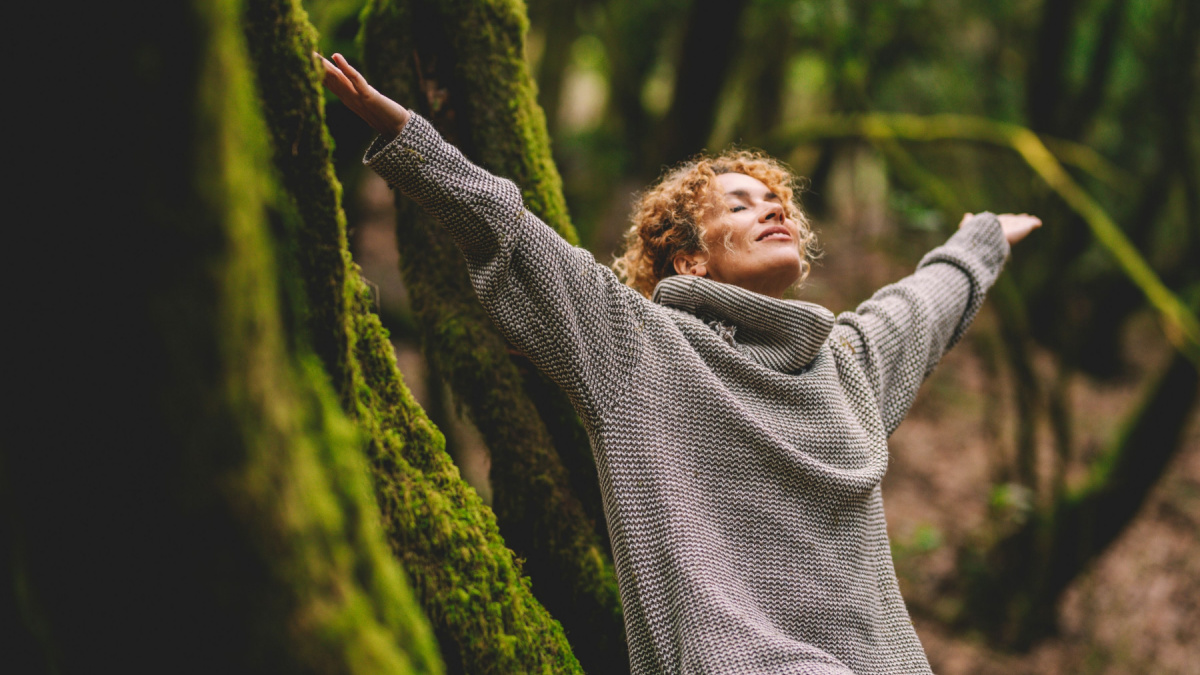 Overjoyed happy woman enjoying the green beautiful nature woods forest around her - concept of female people and healthy natural lifestyle.